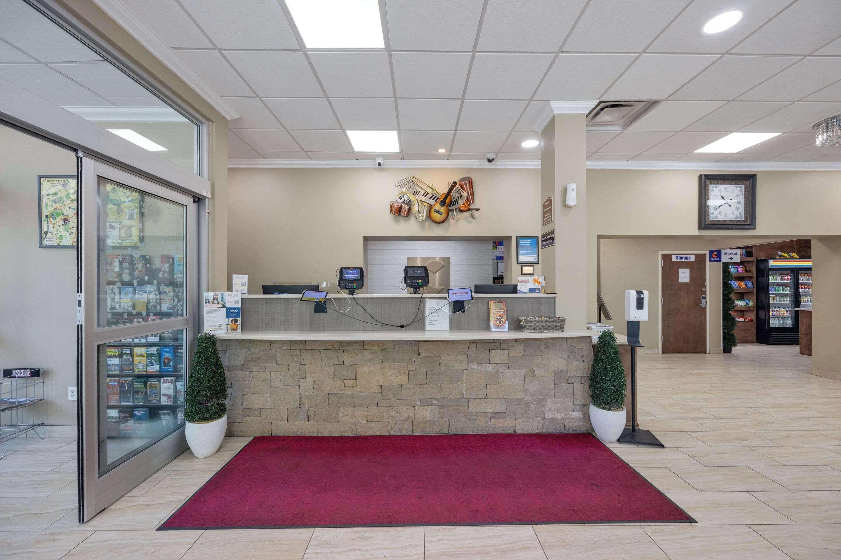 A reception area with a stone counter, a red carpet, a clock, and a vending machine.