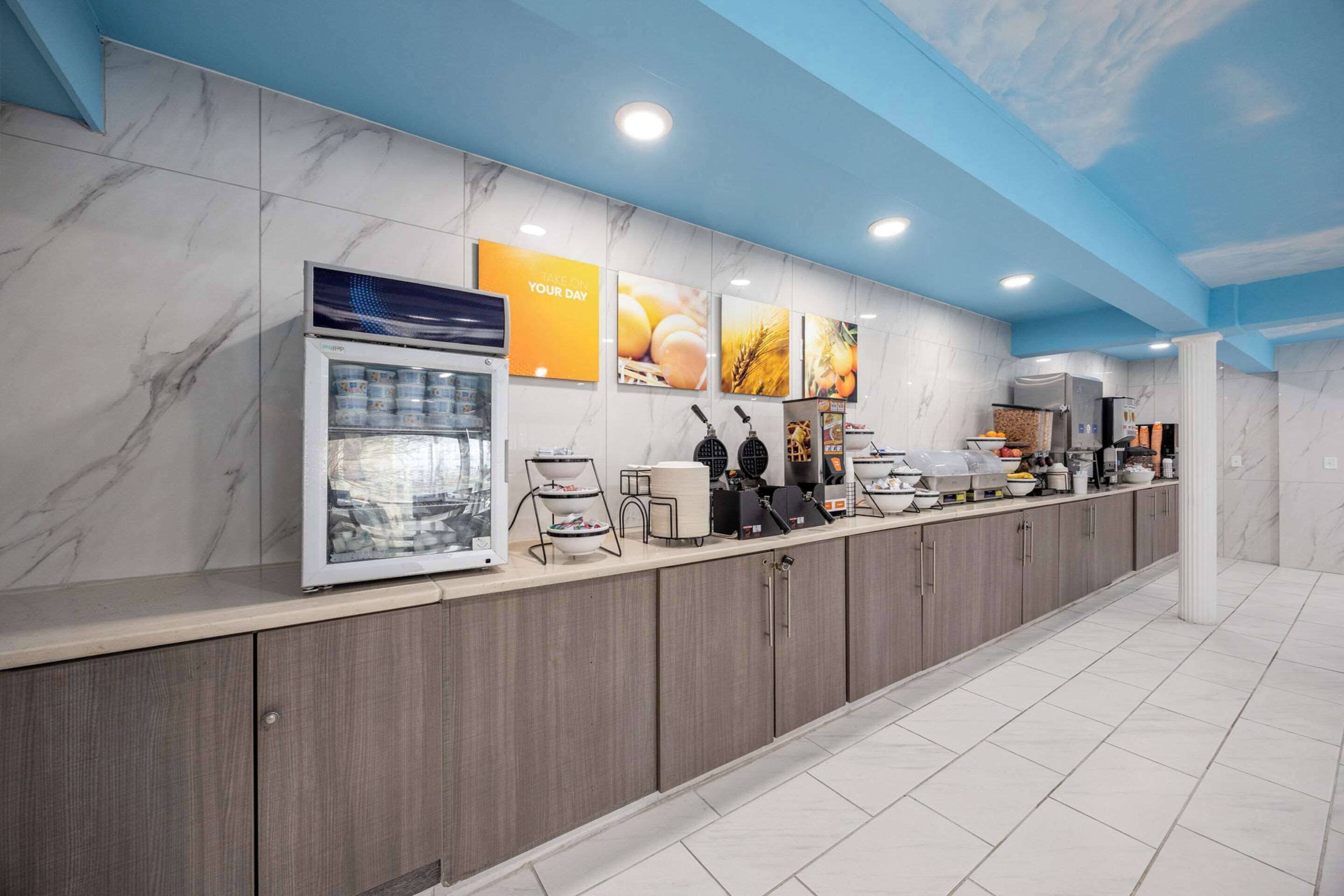 A modern kitchen with marble countertops, a built-in refrigerator, and a coffee station.