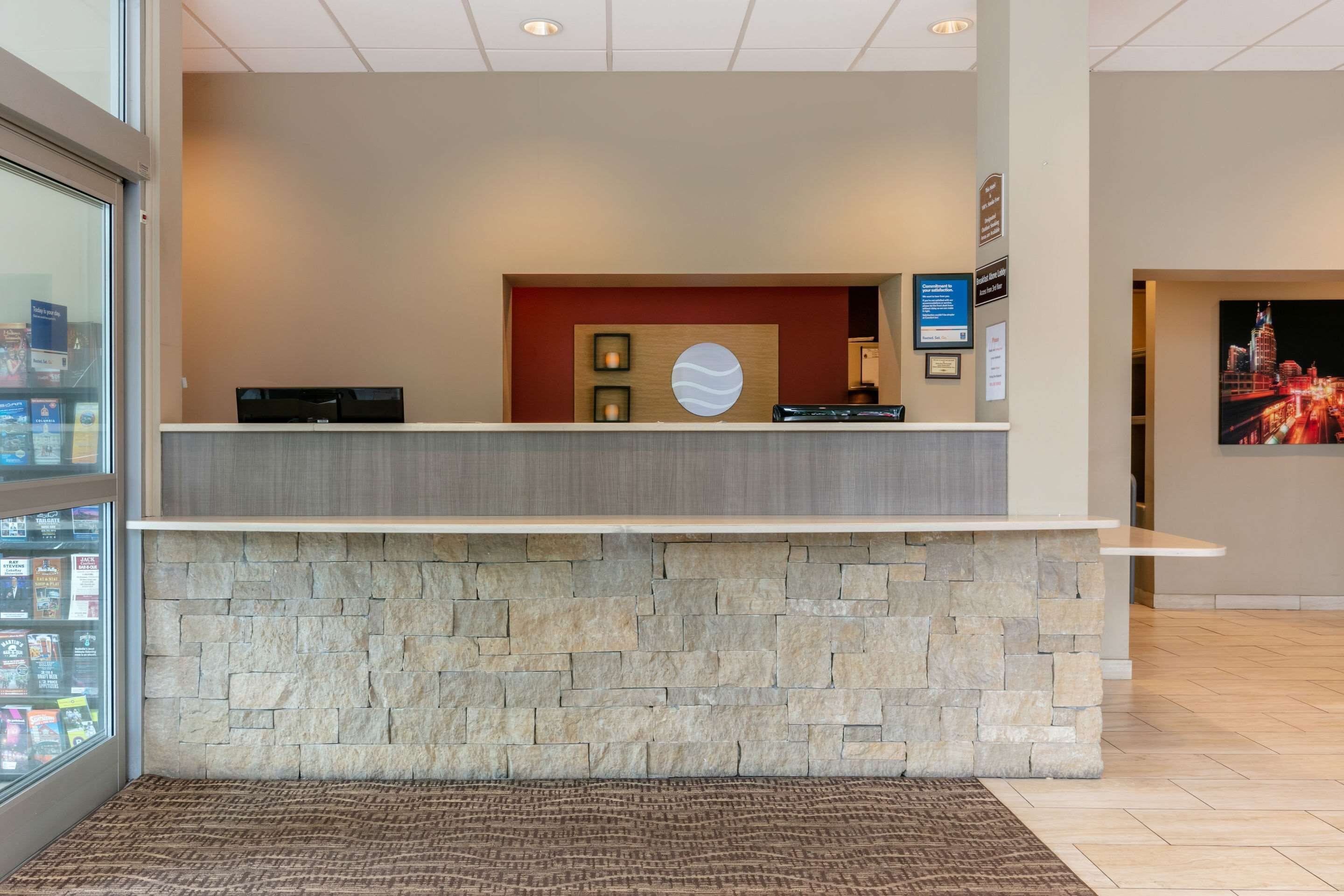 A reception desk with a stone base, a wooden panel with framed pictures, and a cityscape poster on the wall.
