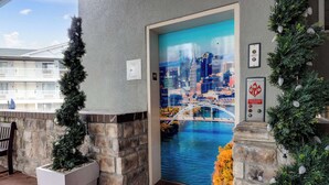 A hotel entrance with a cityscape mural, stone pillars, and a bench.