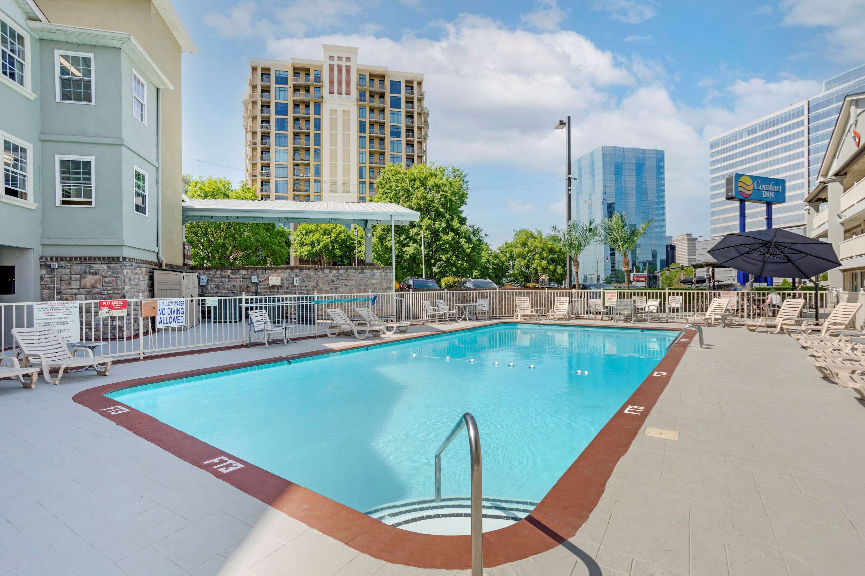 A swimming pool with lounge chairs, a no diving sign, and a Comfort Inn sign in the background.