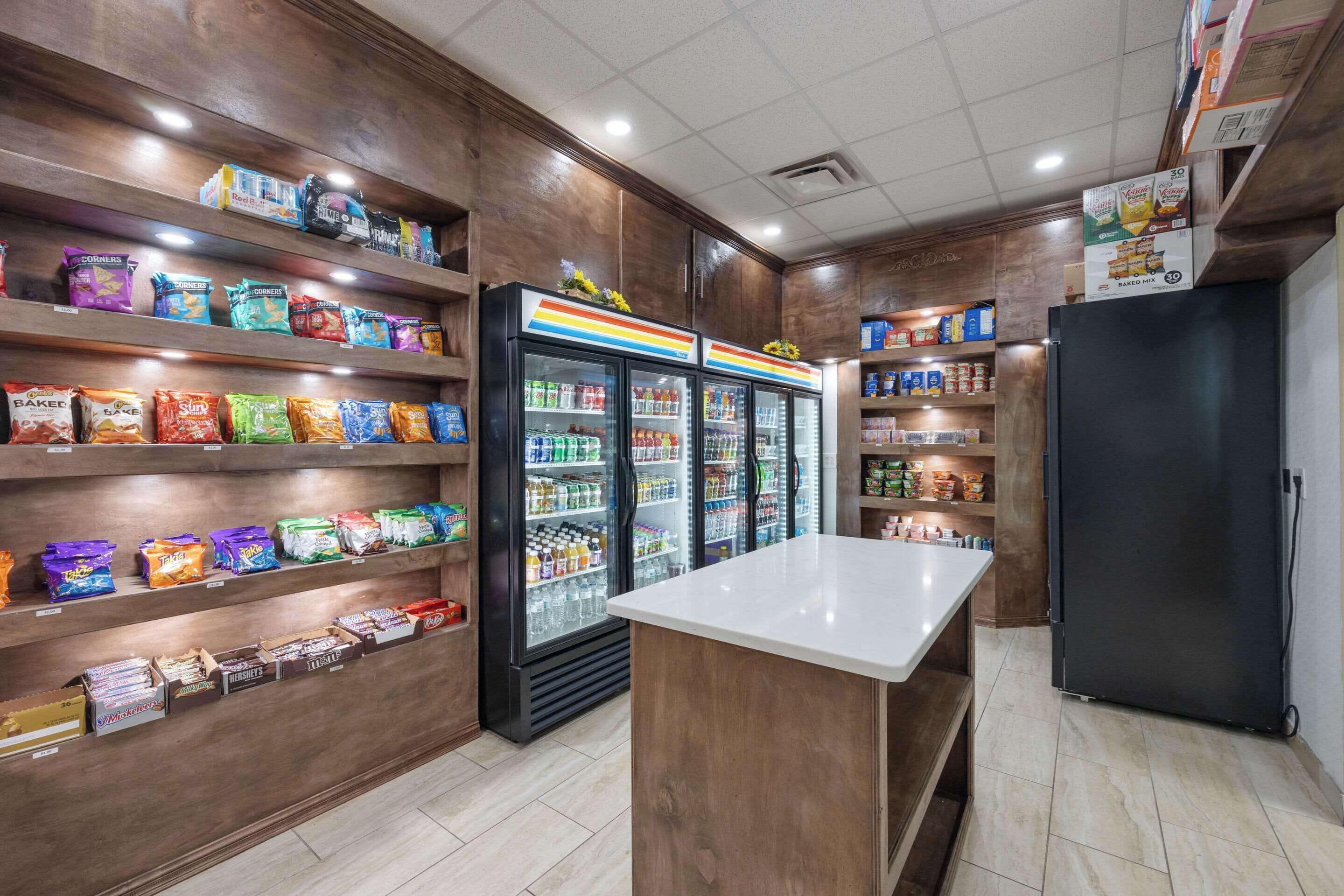 Un espace dédié aux collations et aux boissons, avec des étagères remplies de produits à grignoter et un présentoir réfrigéré pour les boissons.