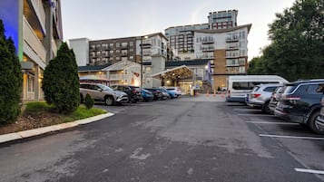 Un hotel con estacionamiento, varios automóviles y un edificio con balcones.