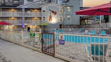 A hotel with a swimming pool, outdoor seating, and a mural of a guitar.