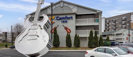 Un hotel Comfort Inn con una gran escultura de guitarra frente a él.