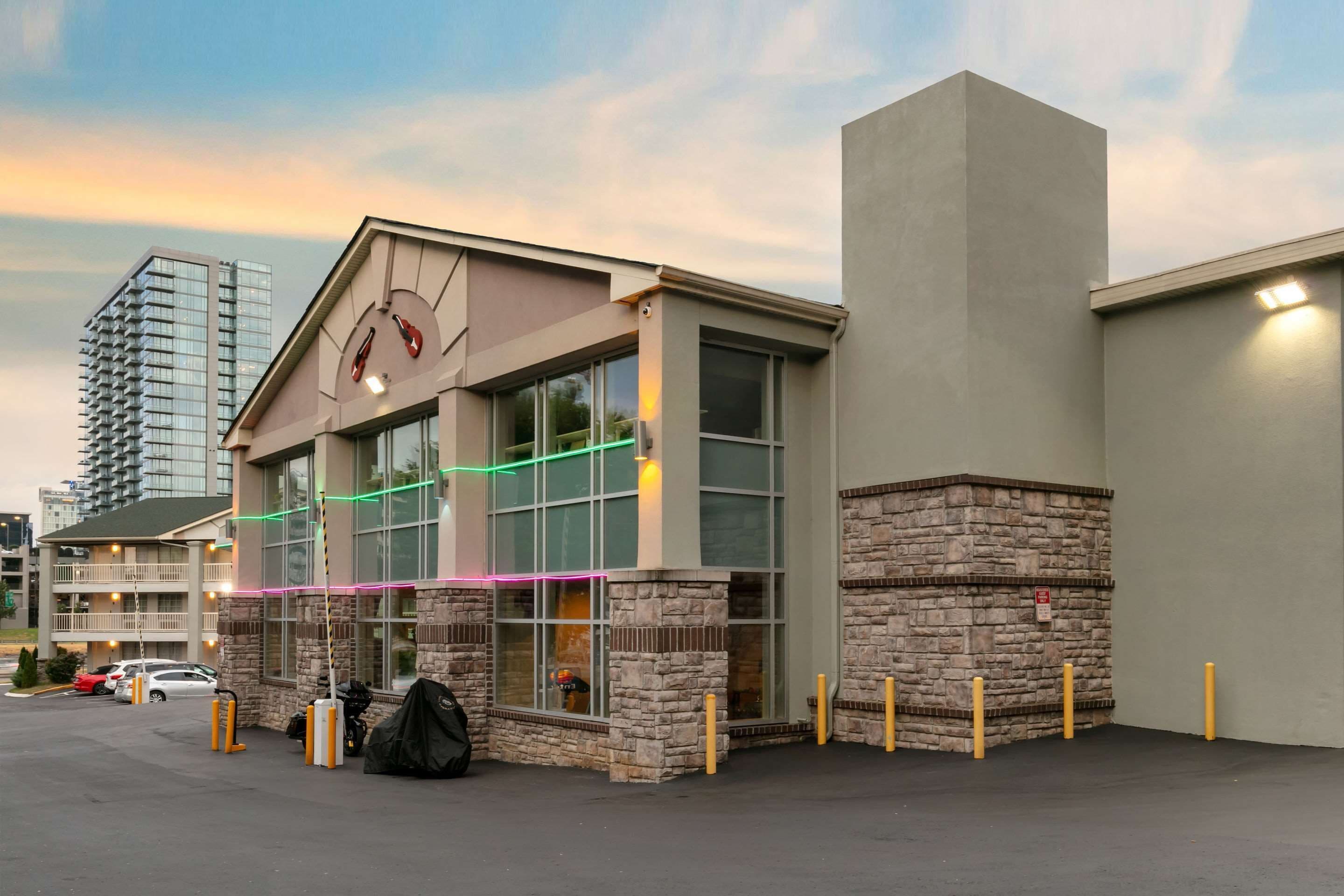 A hotel with a stone facade, large windows, and a parking lot.
