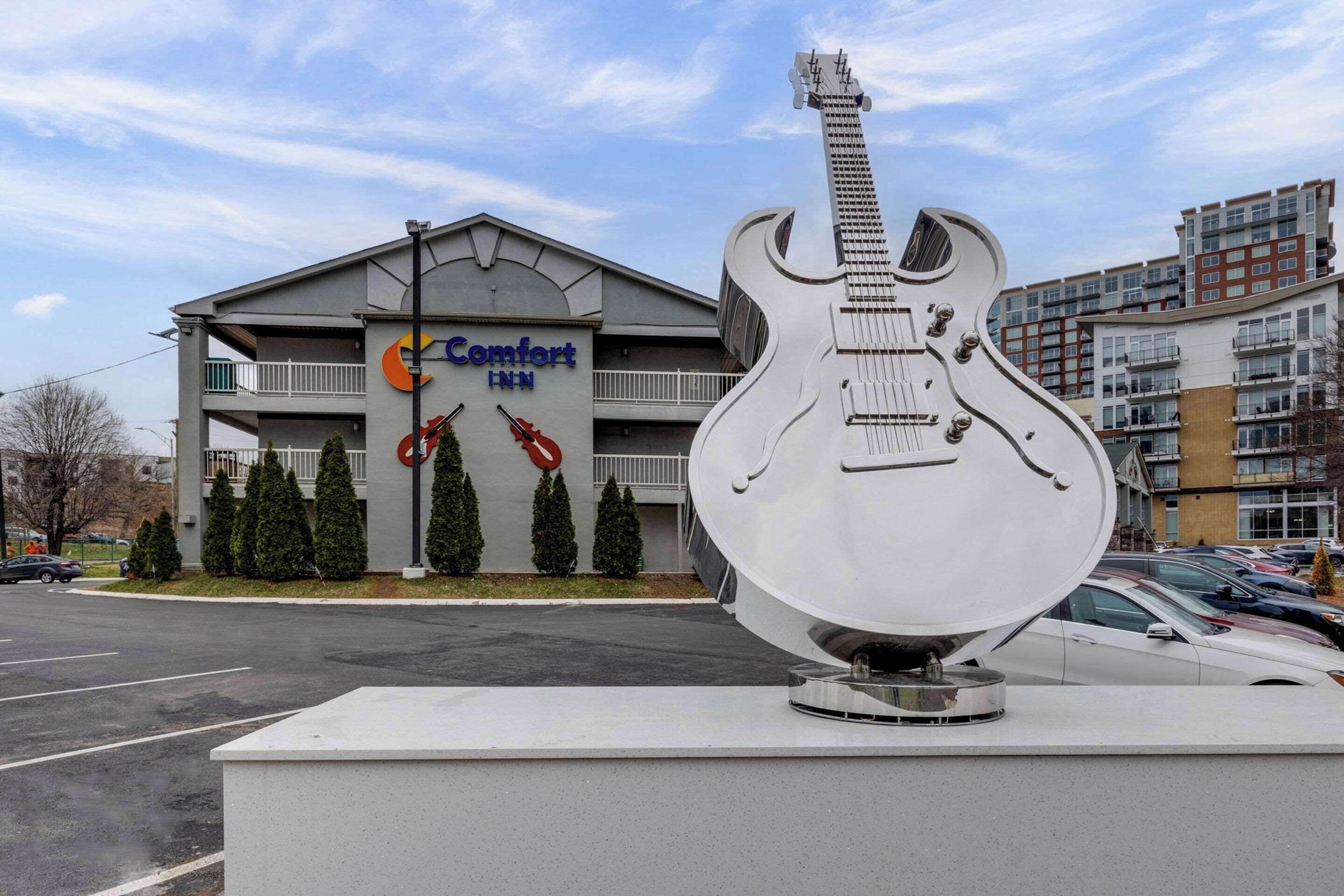 A Comfort Inn hotel with a large guitar sculpture in front.