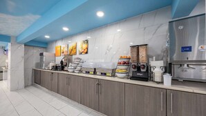 A modern kitchen with marble countertops, a coffee station, and a refrigerator.
