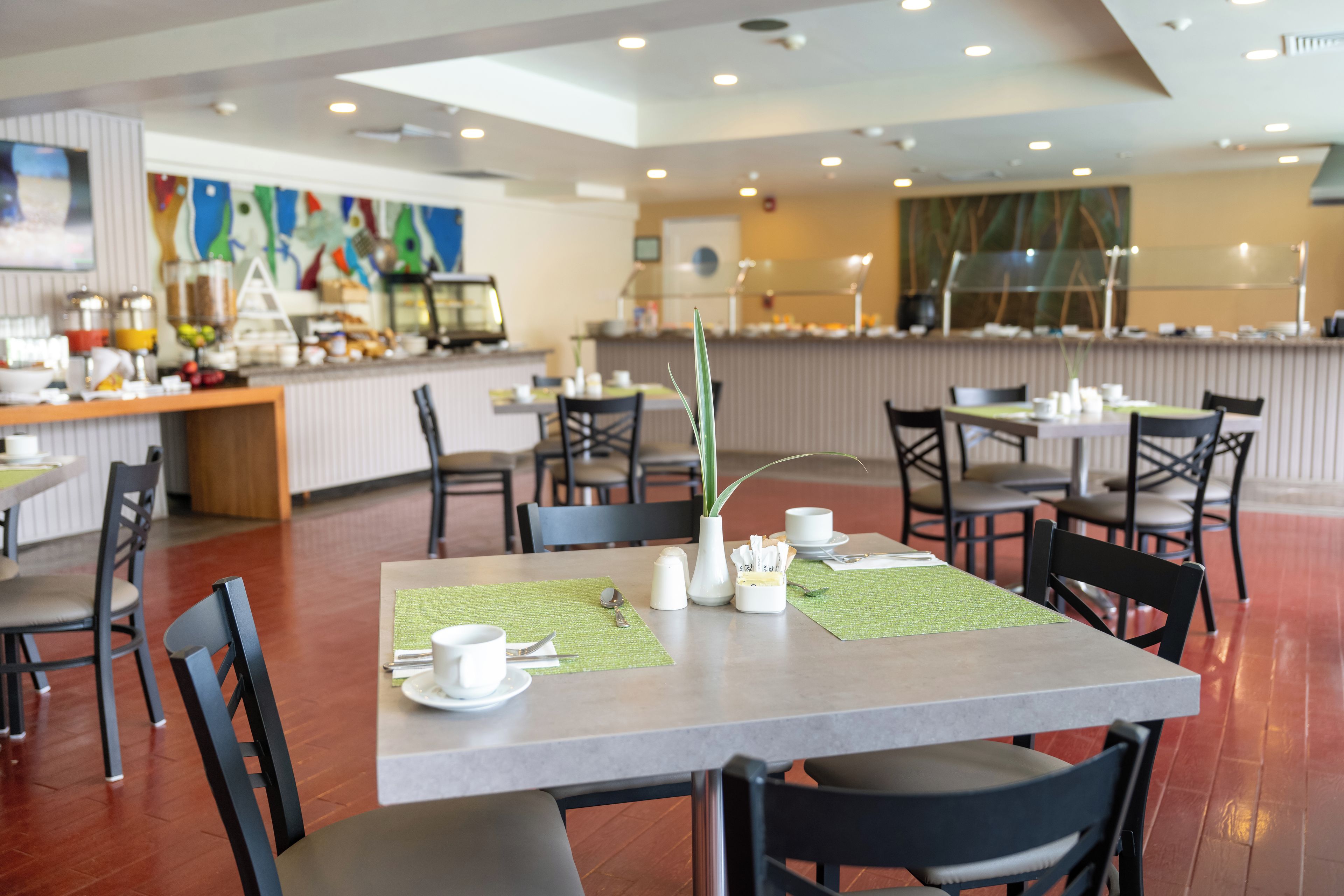 Un ristorante con zona bar, tavoli, sedie e un banco buffet.