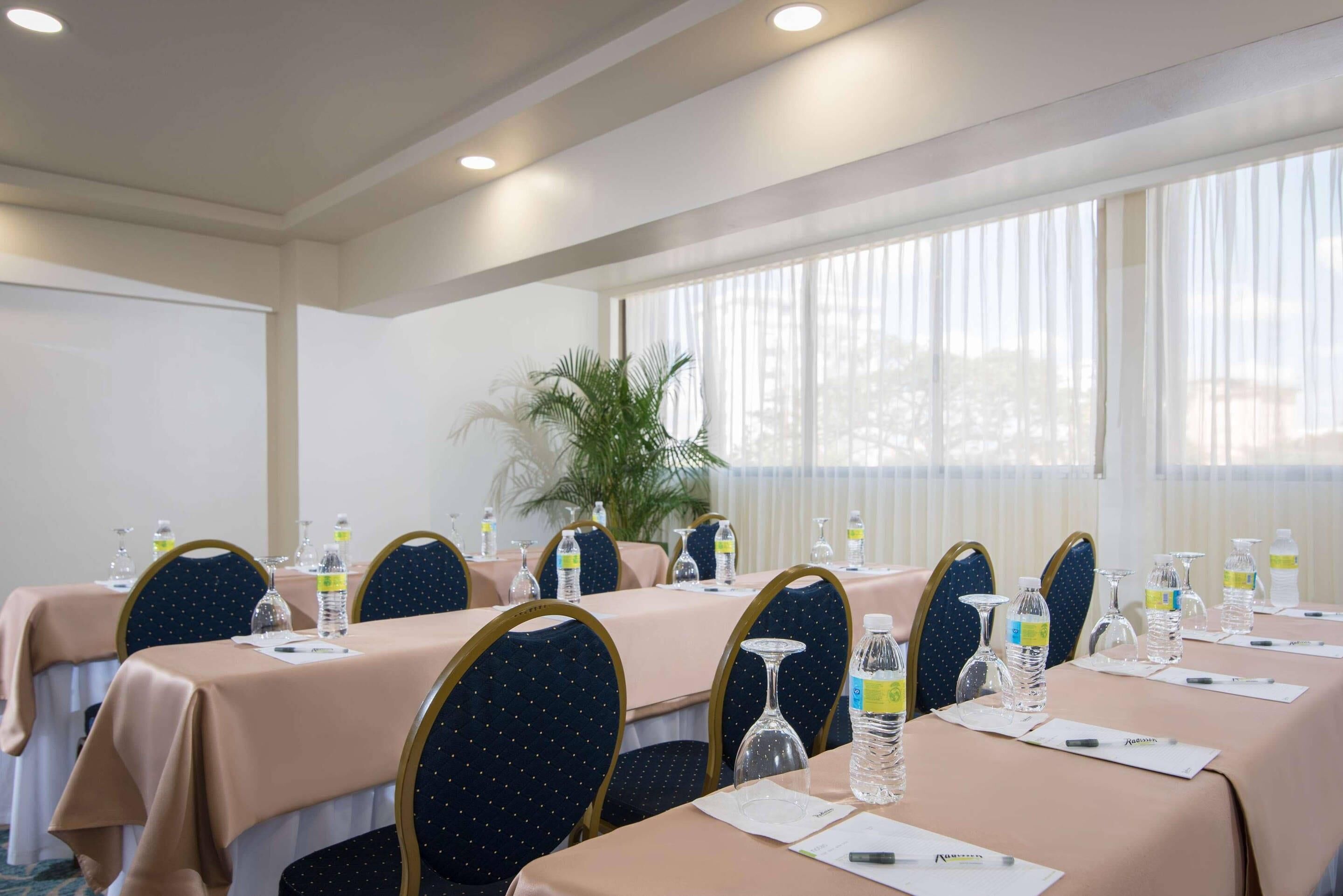 A conference room with tables set for meetings, equipped with water bottles, glasses, and notepads.