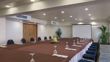 A conference room with a long table, chairs, a projector screen, and a door.