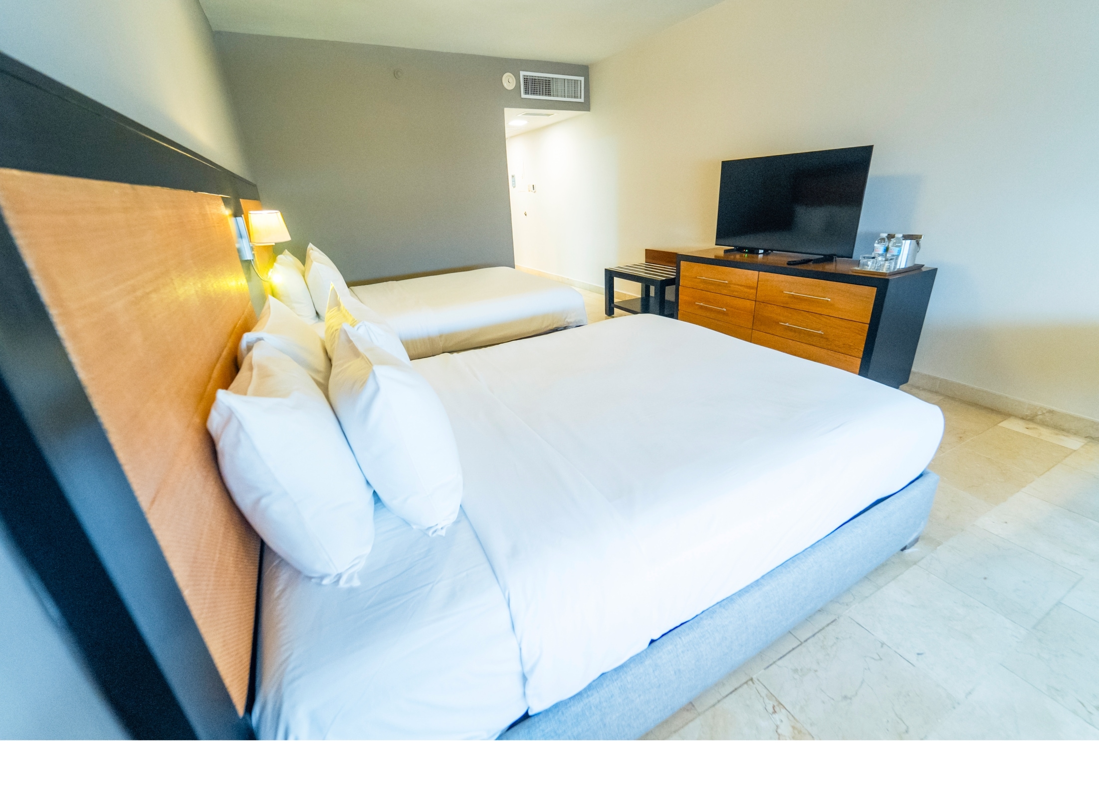 A modern hotel room with a single bed, a TV, and a bedside table.