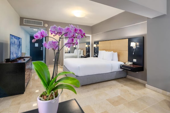 Ein Hotelzimmer mit Bett, Nachttisch, Lampe und einer Topfpflanze.