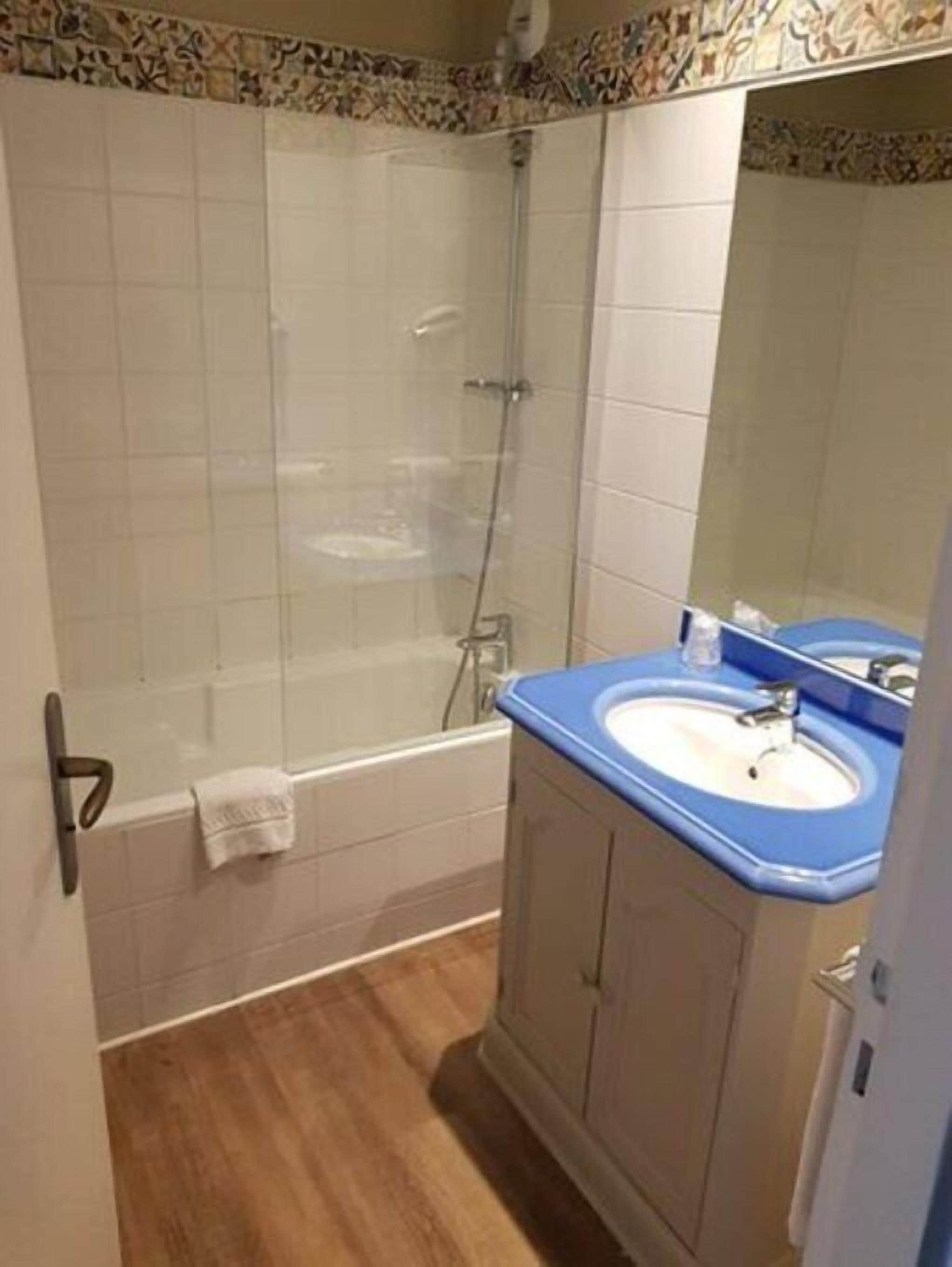 Un baño con ducha, lavamanos y espejo.