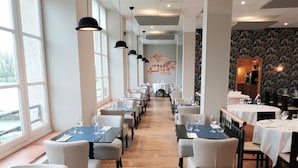 Un restaurante con mesas largas, sillas y lámparas colgantes.