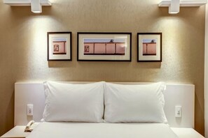 Een hotelkamer met een bed, een nachtkastje en drie ingelijste foto's aan de muur.