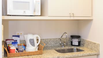 A compact kitchenette with a microwave, kettle, and a small refrigerator.