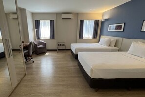 Una habitación de hotel con dos camas, un escritorio, una silla y una mesita.