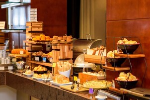A buffet with various food items including bread, pastries, and a grill station.