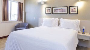 A hotel room with a large bed, a chair, and three framed pictures on the wall. - Comfort Suites Brasilia (Brasília)