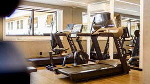 Un gimnasio con múltiples cintas de correr y equipo de ejercicio, ventanas amplias y un diseño interior moderno.