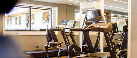A gym with multiple treadmills and exercise equipment, large windows, and a modern interior design.
