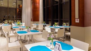 A hotel dining area with tables set for guests, featuring a modern design with white chairs and blue table runners. - Comfort Suites Brasilia (Brasília)