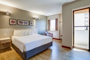 A modern hotel room with a large bed, a desk, a chair, and a balcony. - Comfort Suites Brasilia (Brasília)