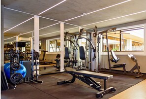 Un gimnasio con equipo de ejercicio variado, que incluye máquinas de pesas, una banca y una cinta de correr.