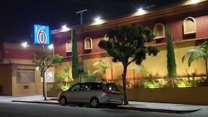 A building with a prominent '6' sign, palm trees, and a parked car. - Motel 6 Los Angeles, CA - Downtown (Los Angeles)