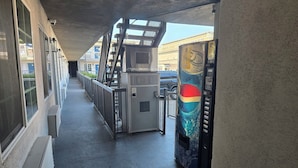 An indoor corridor with a vending machine, a security camera, and a metal staircase. - Motel 6 Los Angeles, CA - Downtown (Los Angeles)