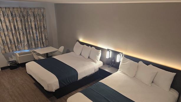 A hotel room with two beds, a desk, and a patterned curtain. - Motel 6 Los Angeles, CA - Downtown (Los Angeles)