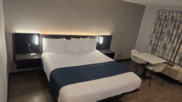 A hotel room with a bed, bedside tables, a desk, and a chair.