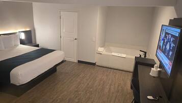 A hotel room with a bed, a desk, a TV, and a bathtub.