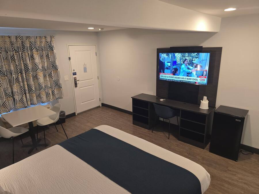 Een hotelkamer met een bed, een bureau, een stoel, een televisie en een klein kastje.