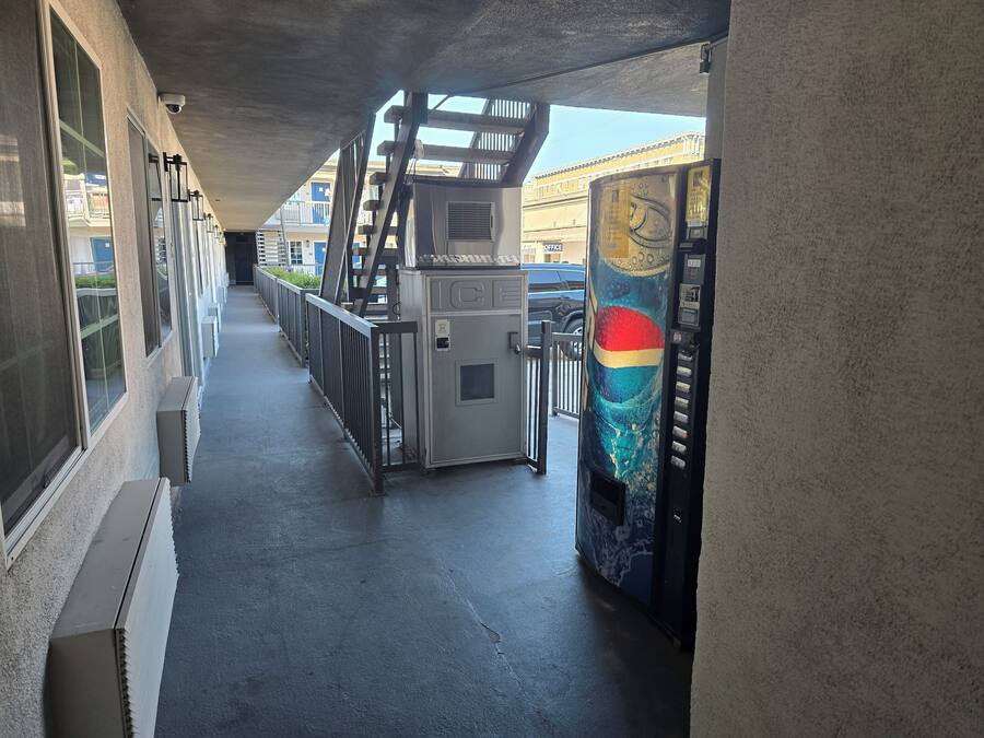 Un pasillo con una máquina expendedora, una cámara de seguridad y una escalera.