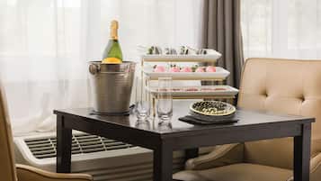 A dining area with a table set for two, a champagne bottle, and a dessert display.