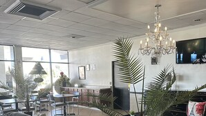 A spacious lobby with a grey sofa, a chandelier, and potted plants. - Econo Lodge Ormond Beach North - Daytona (Ormond Beach)