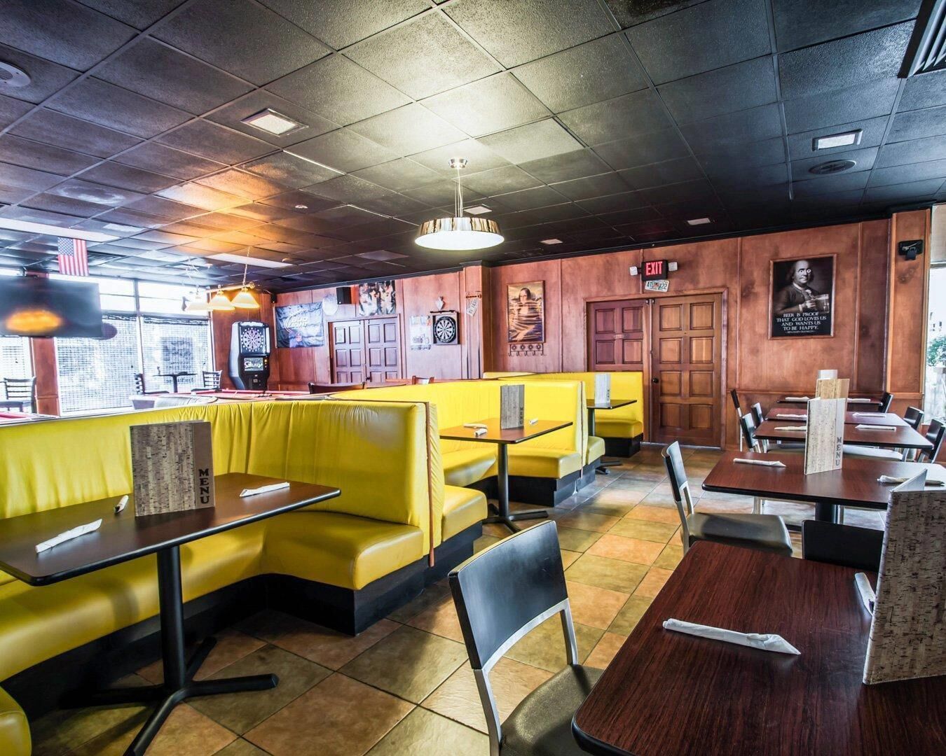 Un restaurant avec des banquettes jaunes, des tables en bois et un sol carrelé.