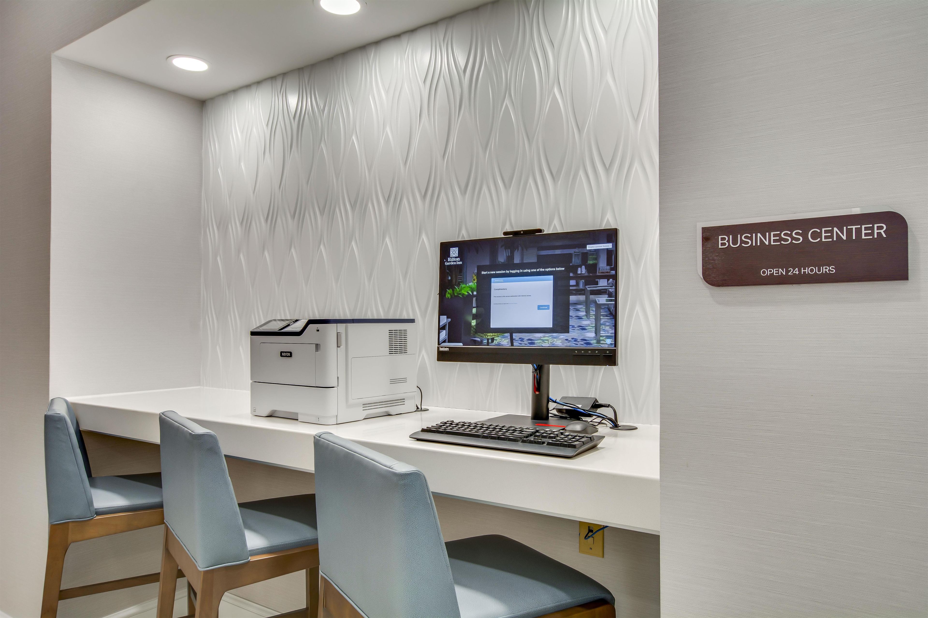 Centro de negocios con una computadora de escritorio, impresora y dos sillas.