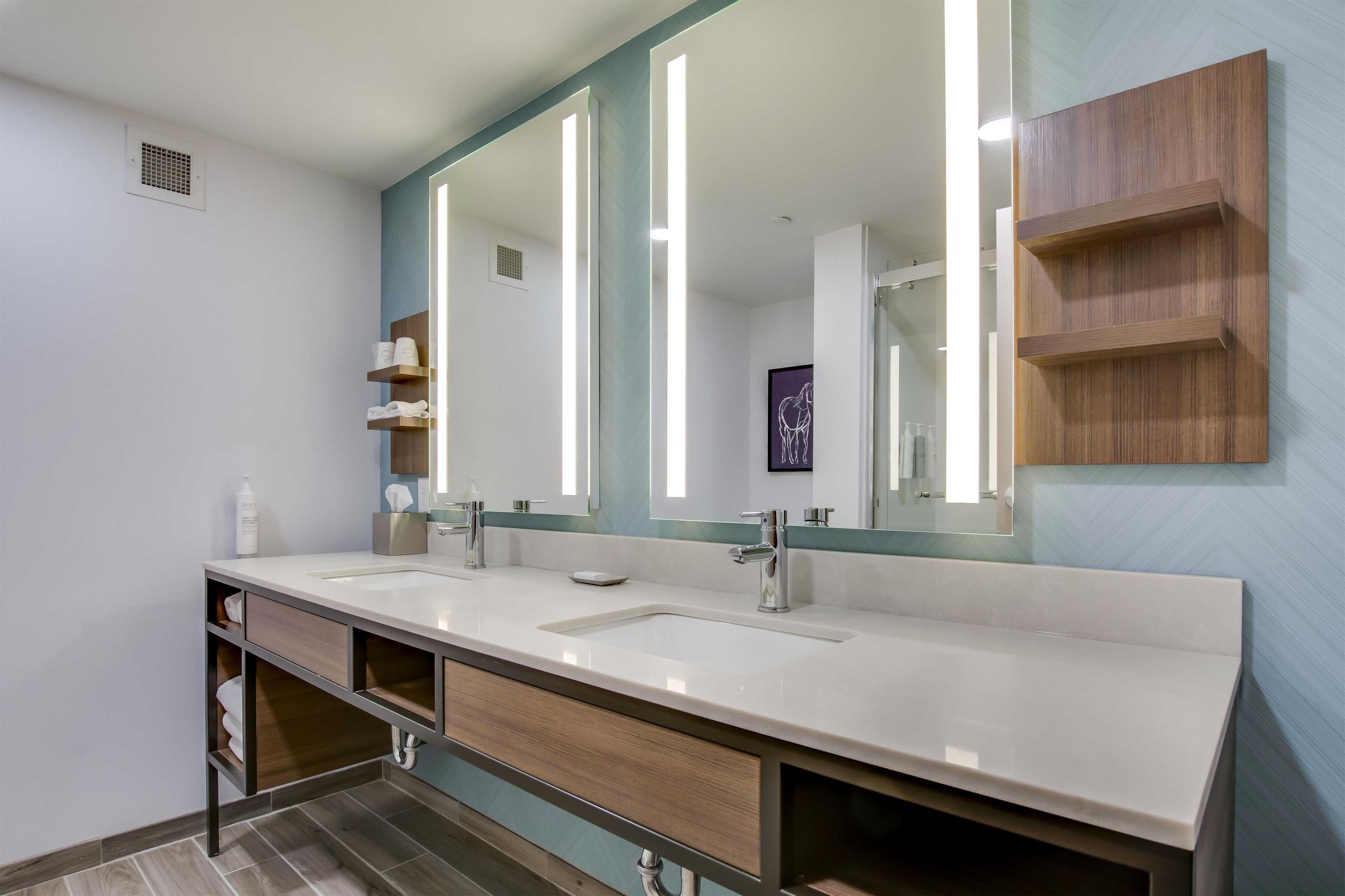 Un baño moderno con dos lavamanos, un espejo grande y un mueble de tocador de madera.