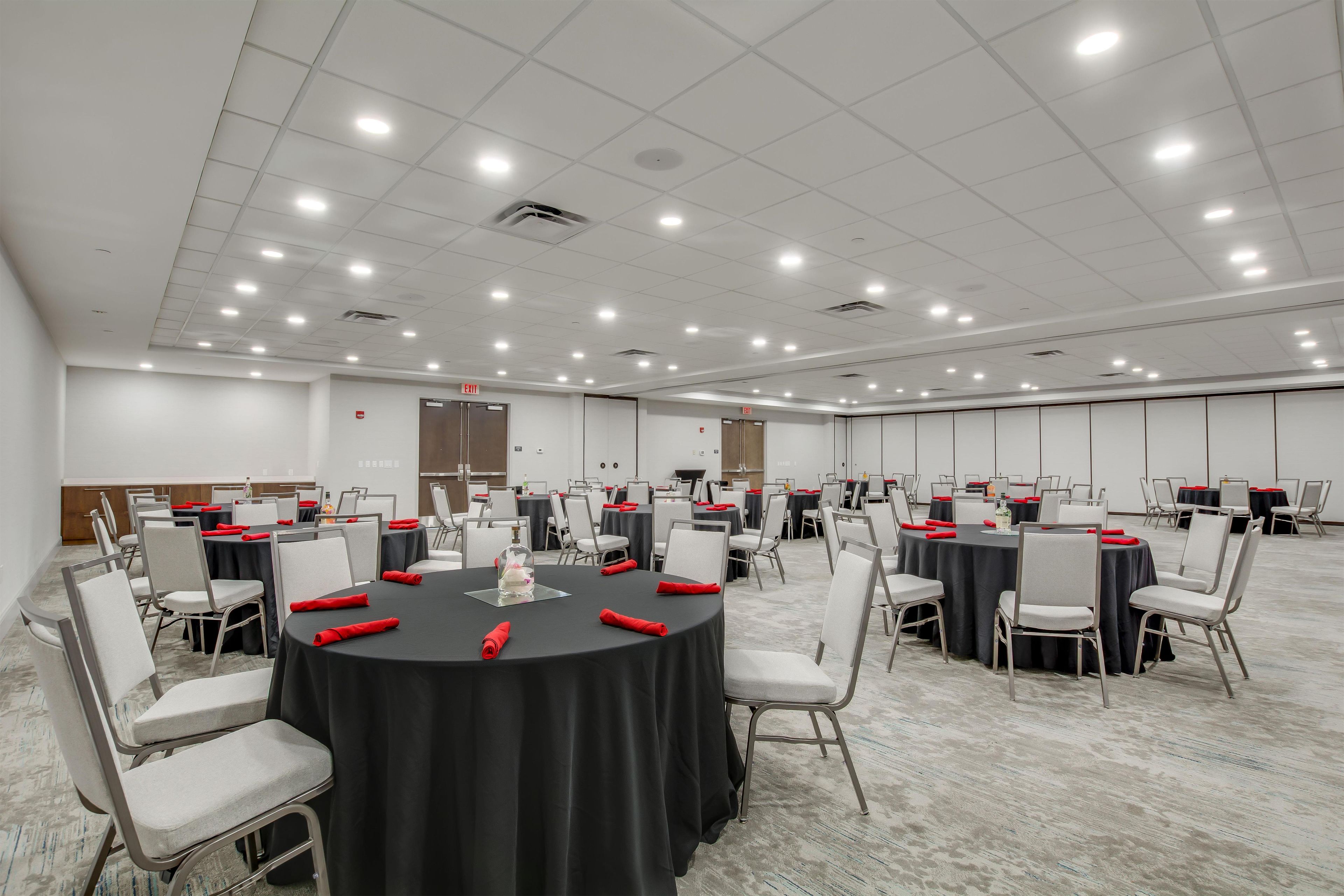 A conference room with multiple tables, chairs, and a carpeted floor.