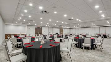 A conference room with multiple tables, chairs, and a carpeted floor.
