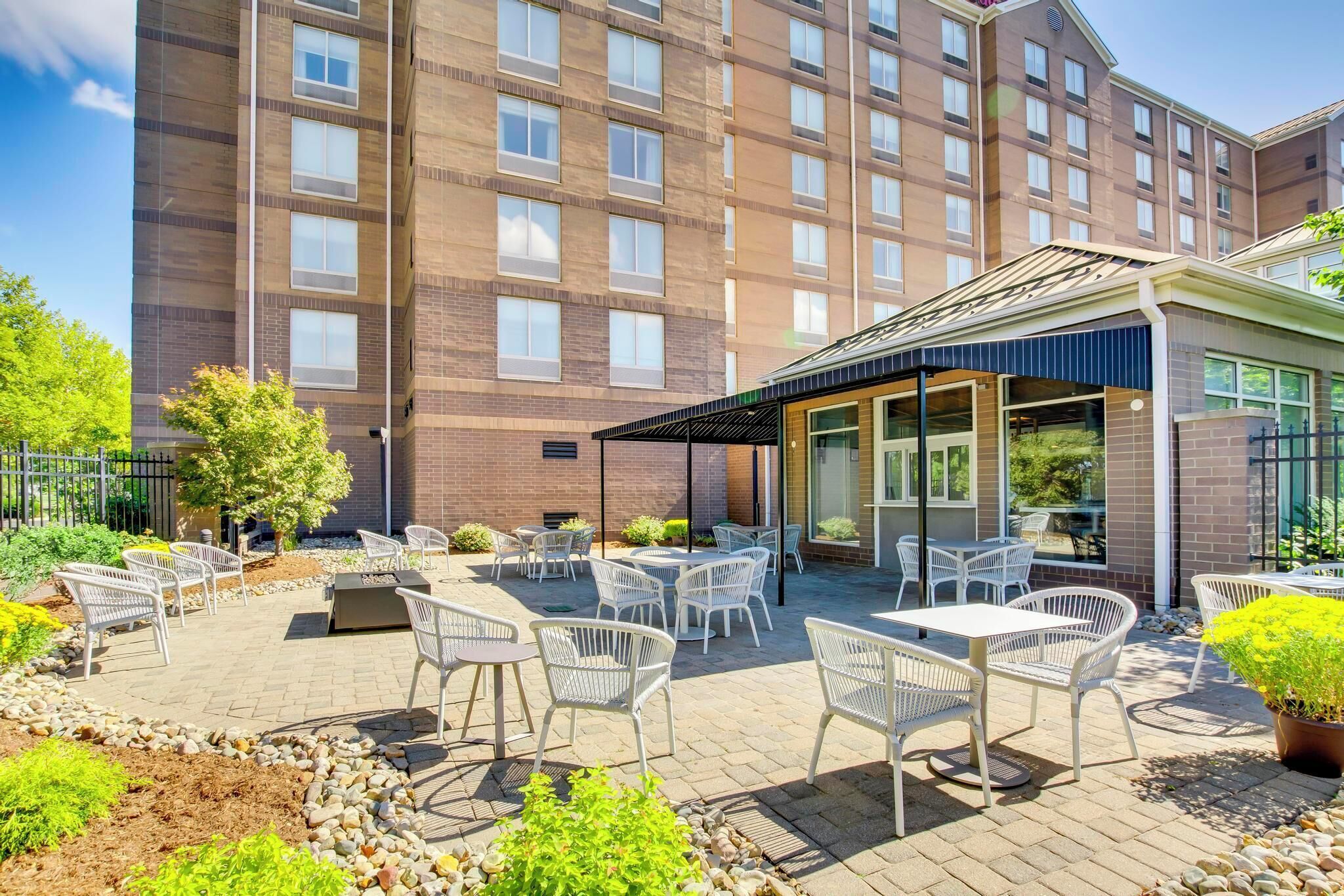 Ein Hotel mit einer Terrassenanlage, die Sitzgelegenheiten im Freien und einen überdachten Bereich bietet.