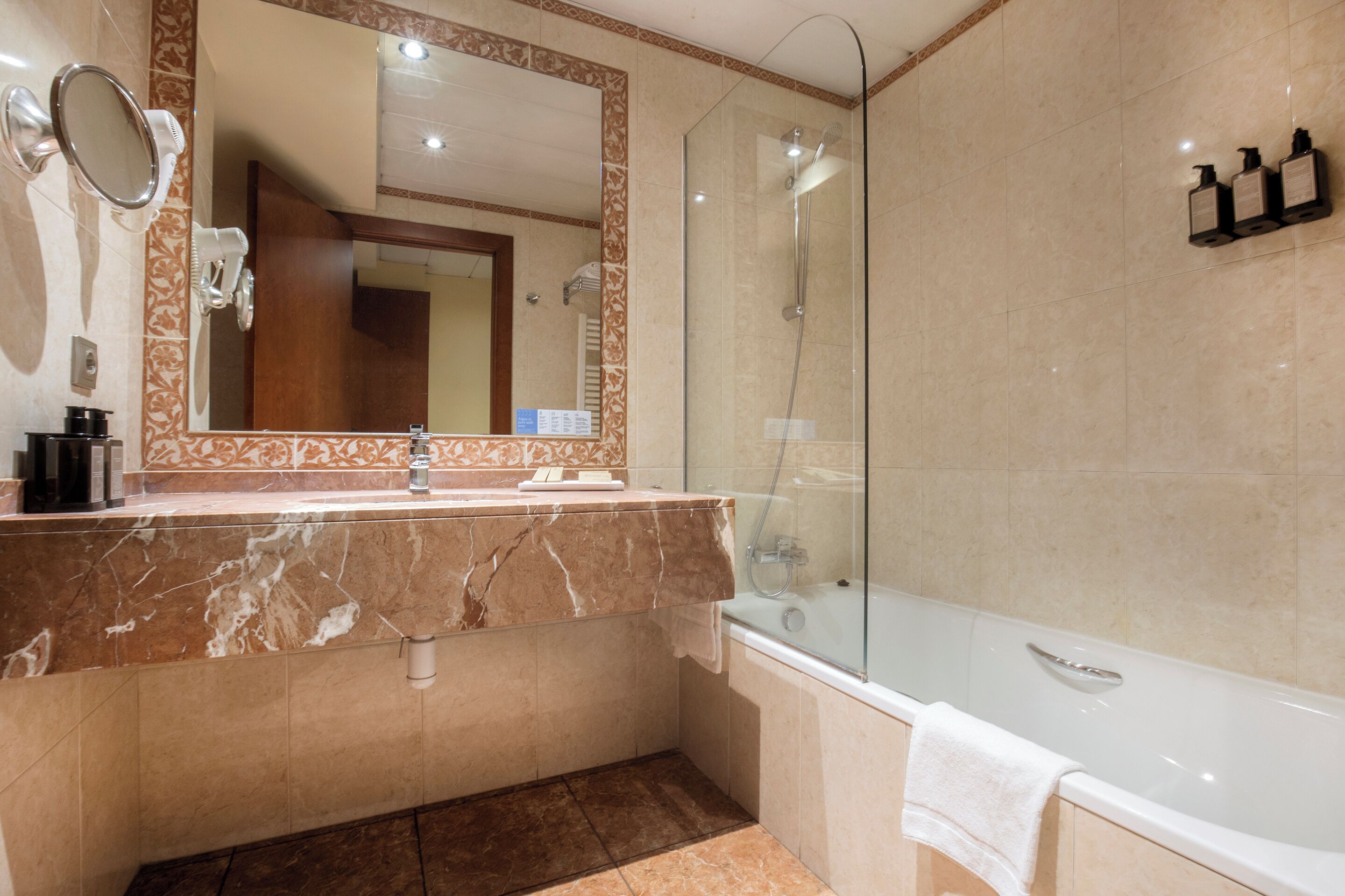 A bathroom with a marble vanity, a glass shower enclosure, and a large mirror.
