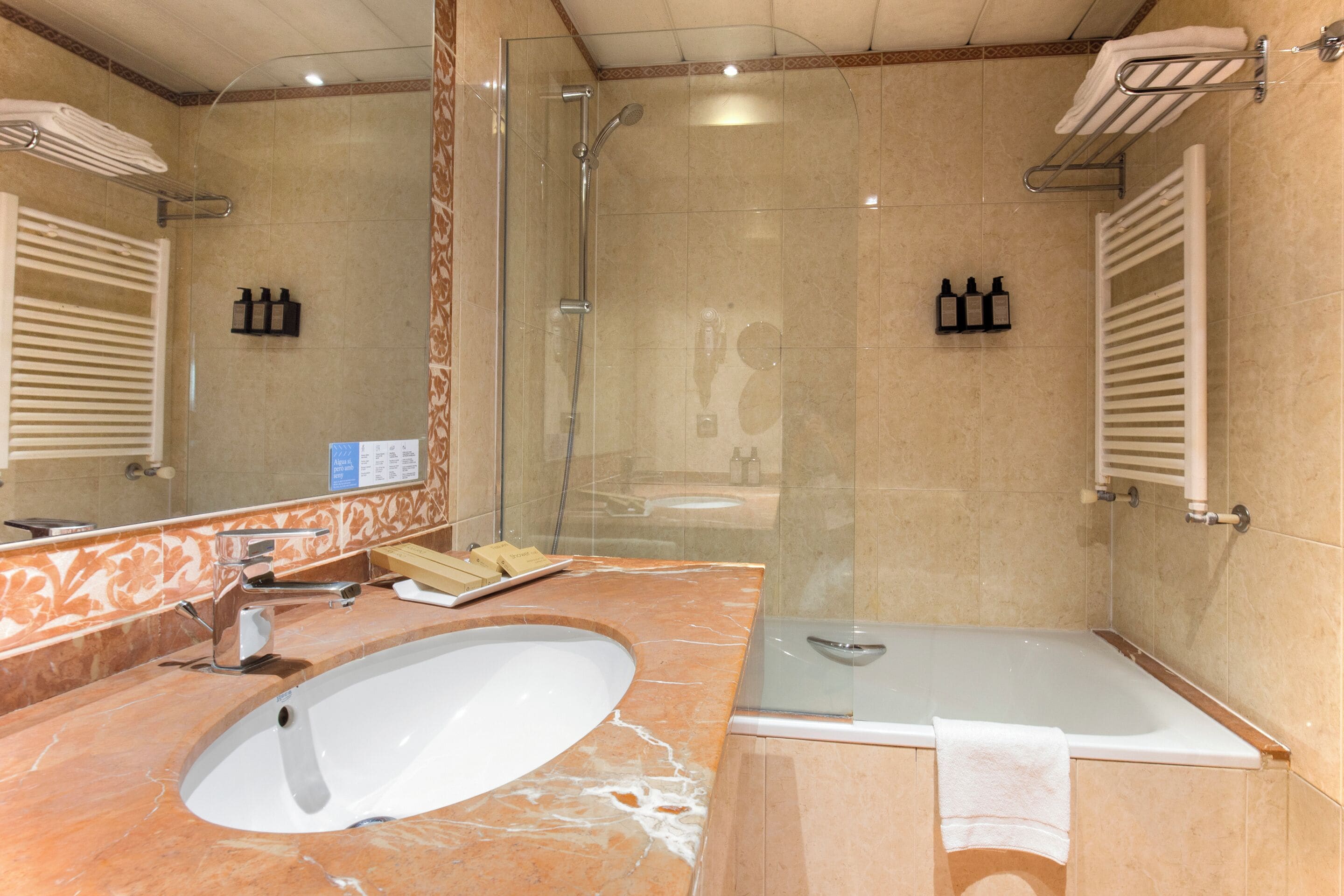 A bathroom with a glass-enclosed shower, a sink, and a bathtub.