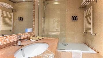 Un baño con ducha envuelta en vidrio, lavamanos y bañera.