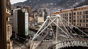 Un puente con la inscripción "Orrà La Vella" y un paisaje urbano con edificios y montañas al fondo.