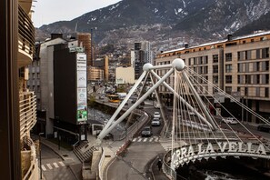A bridge with the inscription "Orrà La Vella" and a cityscape with buildings and mountains in the background.