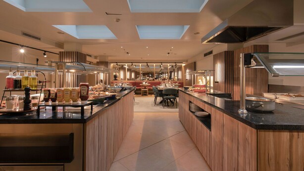 A modern kitchen with skylights, a central island, and a dining area in the background.
